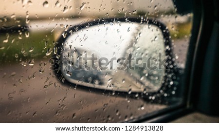 car mirror through glass with raindrops, raindrops on the glass