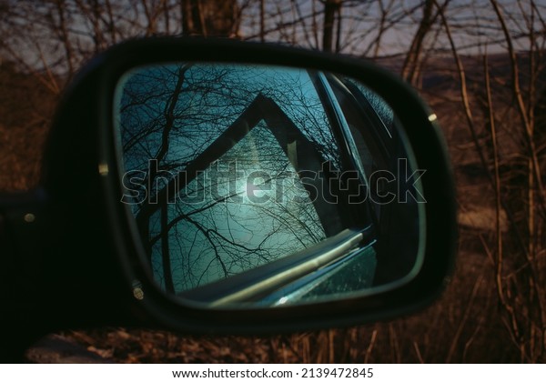 Car mirror through the\
window on a nice spring day. Trees and sky reflected. Safety\
driving concept