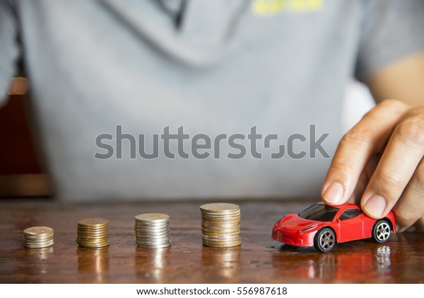 Car model and coin\
stack, with  hand