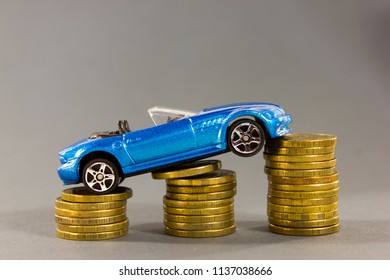 Car Model On  Background Of Coins. Concept Of Leasing, Auto Loan, Auto Insurance, Taxes.