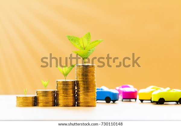 Car model and stack coin with plant growing on\
the top for collect interest put on the desk in the office, loan\
and saving for buy a new car and business investment a chattel in\
the future concept.