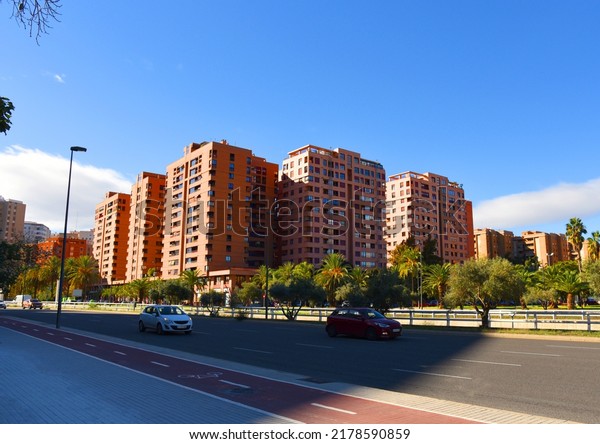 Car in motion on road in city Valencia. City\
street, road traffic, cars on road. Urban buil architecture.\
Multi-storey residential buildings with palm trees in city center.\
Bike path at traffic road. 