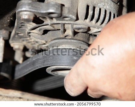 Car motor alternator unstrung belt mounting and tension - service man hand checks electric system of the vehicle before eliminator repair