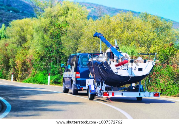 Car with a motor boat at the\
trailer on the road of Olbia, Costa Smeralda, Sardinia,\
Italy