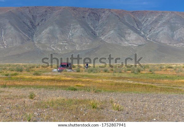 Car and motorbike on road in the desert mountain\
of the Mongolia