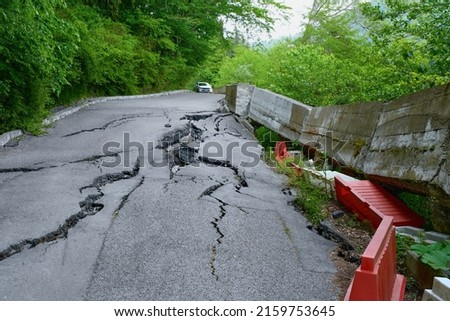The car moves to the destroyed road surface. Landslide. Sochi, the road in front of the park yew-boxwood grove.