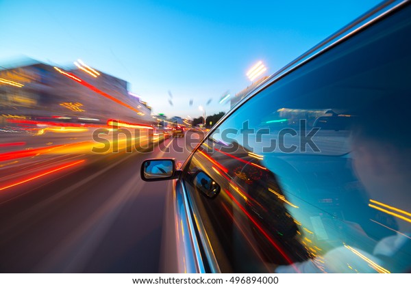 The car moves at great speed at the\
night. Blured road with lights with car on high\
speed.