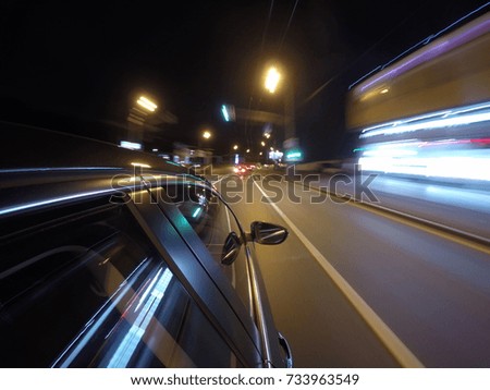 The car is moving at high speed on the night road in the city. Side camera location on the car body.