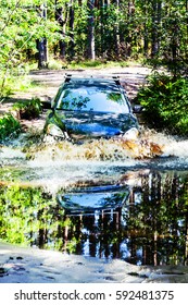 A car moving through a large puddle in the woods