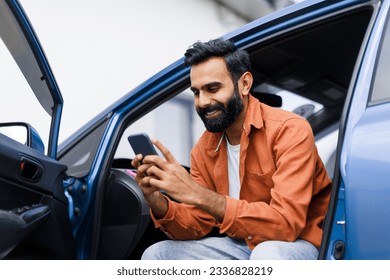 Car Navigation Application. Happy Middle Eastern Man Using Phone Sitting In Auto With Opened Door, Searching Best Way Via Mobile Gps Navigator App, Posing With Gadget In Luxury Automobile - Powered by Shutterstock