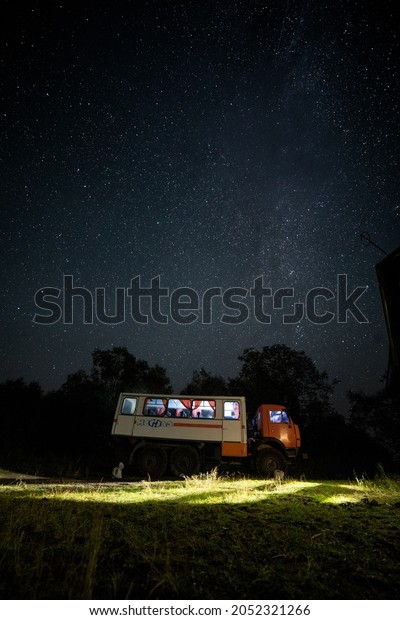 car in the night against the background of stars\
and the light from the\
windows
