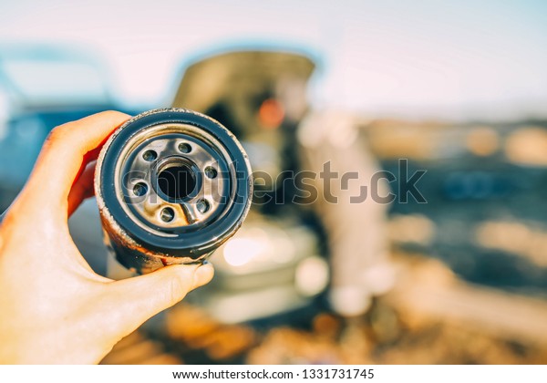car oil filter in auto\
mechanic\'s hand. concept of replacing engine oil between climatic\
seasons.