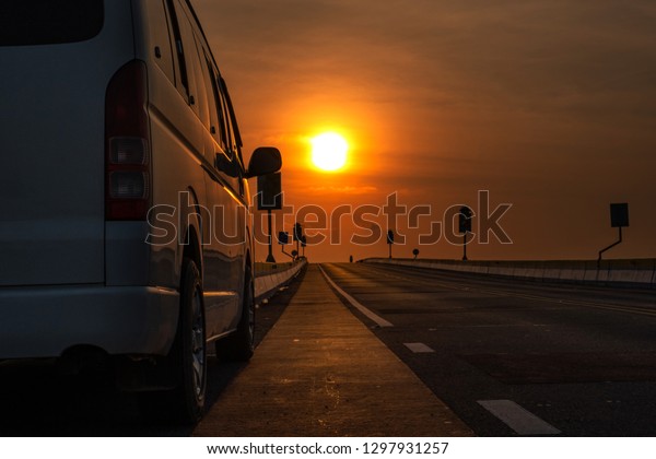 Car on along the road. Sunset and lightning.\
Sunset Over Asphalt Road pass through the lake in Talay noi lake,\
Pattalung province\
Thailand.