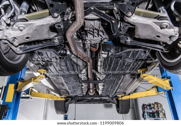 Car on a Heavy\
Duty Industrial Lift. Repairing Broken Vehicle. Auto Service Theme.\
Looking Undercarriage. 