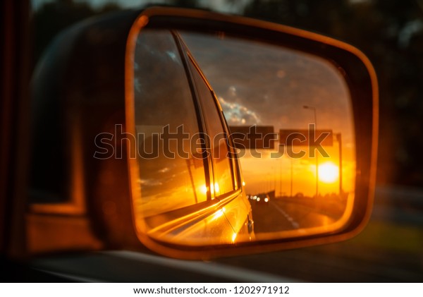 car on highway. sunset in car mirror reflection.\
road trip