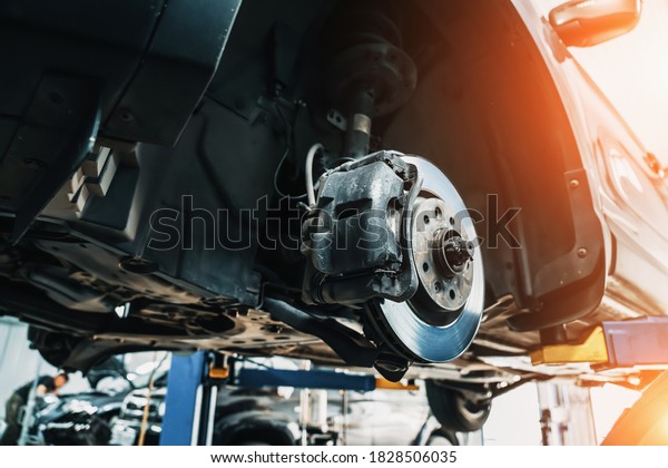Car on lift in car service with wheels\
removed for repair and\
maintenance