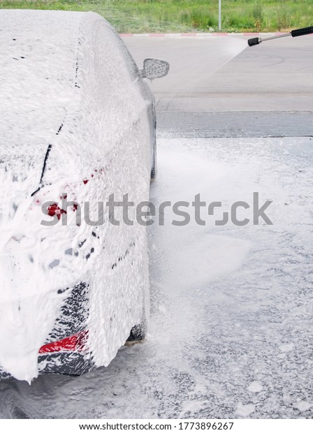 car on the side in the foam and bubbles from the\
detergent in the car wash