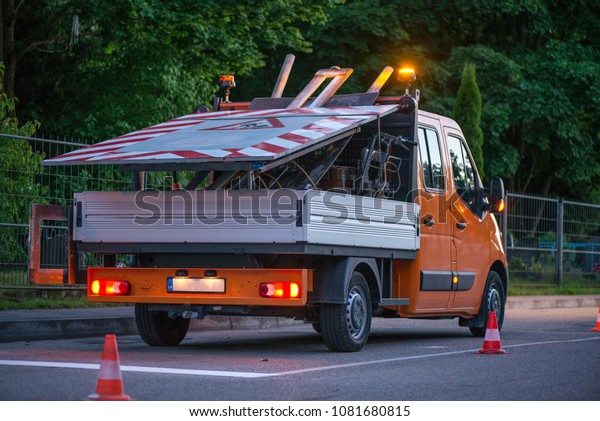 Car on side of road with warning lights. Road\
construction works. Traffic line painting. Painting white street\
lines on pedestrian crossing. Road cones with orange, white stripes\
standing on asphalt.
