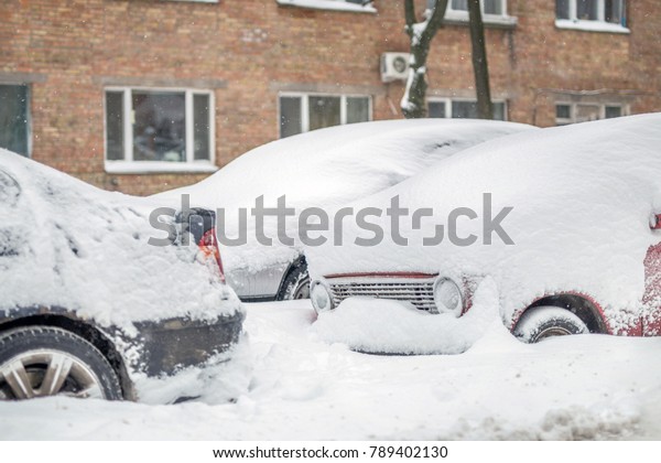 Car on a street\
covered with big snow\
layer.