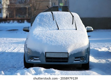 A car on the street of a town covered with snow in the winter season. 