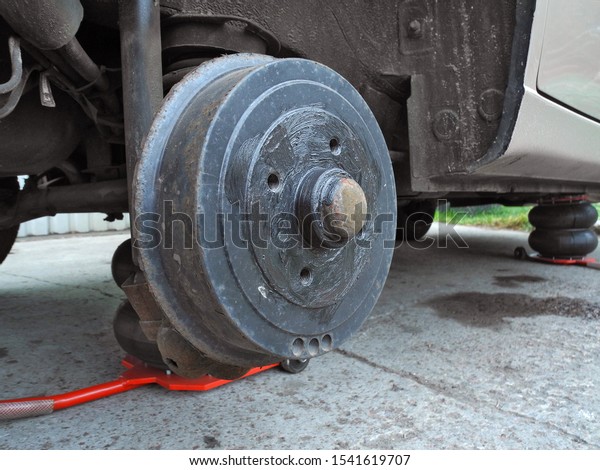 Car on tire\
mounting with removed wheel  on pneumatic jack. Wheel hub closeup.\
Seasonal tire change. Breakdown wheel. Car service concept.        \
                          