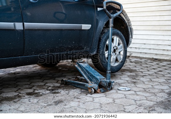 car on tire mounting\
with removed wheel on pneumatic jack, seasonal tire change, car\
service concept
