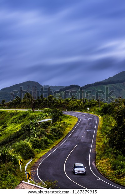 A car on the winding valley road. Driving in the\
beautiful nature.
