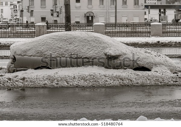 Car on winter road covered with snow side view.\
Vehicle on snowy alley in the morning after snowfall in city. A\
street with car covered with snow in wintertime. Parked car\
outdoors, weather problem.