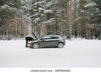 A Car With An Open Hood On The Background Of A Winter Forest