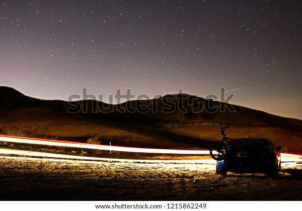A car overlooking a lightly traveled road and a\
starlit night