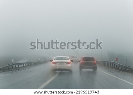 Car overtake rules violation crossing double lane. traffic on foggy misty rainy highway intercity road low poor visibility cold winter autumn day. Seasonal bad rainy weather accident danger warning