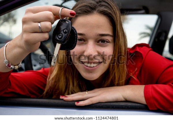 car owner proudly showing car keys.\
happy girl buying a car.  vehicle ownership\
concept