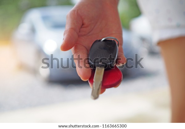 The car owner is standing the car keys to the buyer.\
Used car sales    