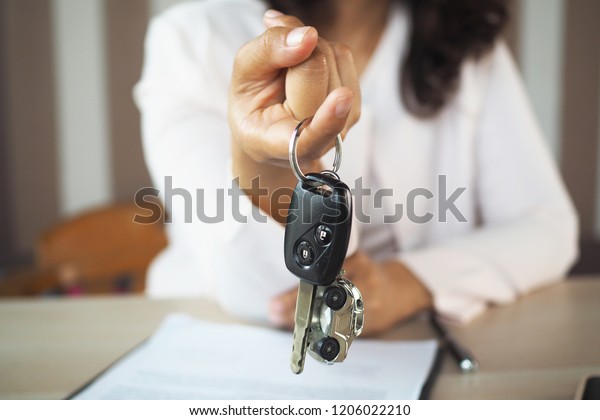 The car owner is standing the car keys to the buyer.\
Used car sales  