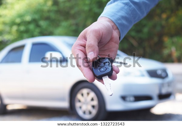The car owner is standing the car keys to the buyer.\
Used car sales     