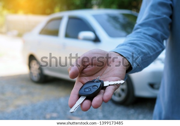 The car owner is standing the car keys to the buyer.\
Used car sales    