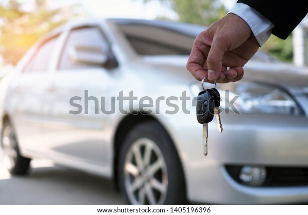 The car owner is standing the car keys to the buyer.\
Used car sales  