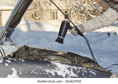 Car Owner Warming Up A Motor Using Hairdryer In Cold Winter Outdoors                               