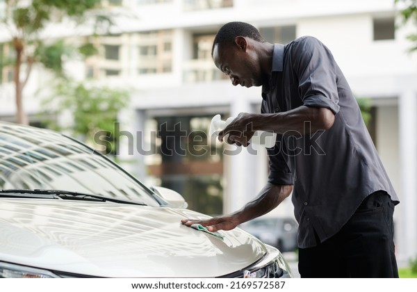 Car owner wiping hood with detergent to remove bug\
stains off hood