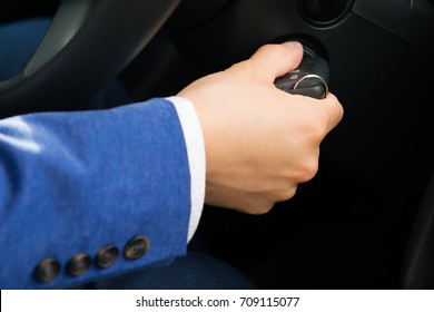 The Car Owner's Hand Turns The Car's Ignition Key, In A Blue Suit