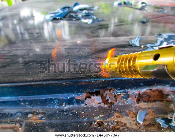 Car paint technician removes
old paint from car roof with gas cans with manual gas torch burner
(blowtorch) on spray can and scraper. Close Up.Selective focus,
Blurred.