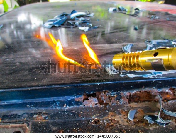 Car paint technician removes
old paint from car roof with gas cans with manual gas torch burner
(blowtorch) on spray can and scraper. Close Up.Selective focus,
Blurred.