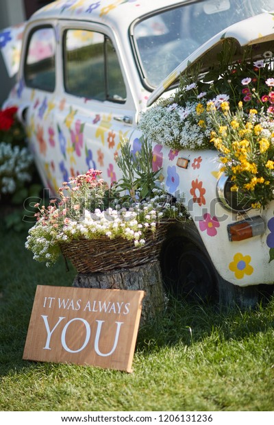 car painted with flowers, surrounded by bouquets of\
flowers, wedding decor