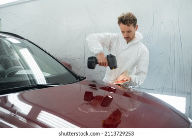 Car Painter Man Determines The Correct Tone Of A Vehicle Body Colour Using A Special Colorist's Lamp. Auto Body Repairman In Garage