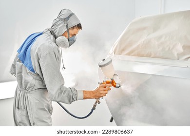 Car painter in special painting chamber, wearing costume and protective gear. Car service station. Restoring a car after an accident - Powered by Shutterstock