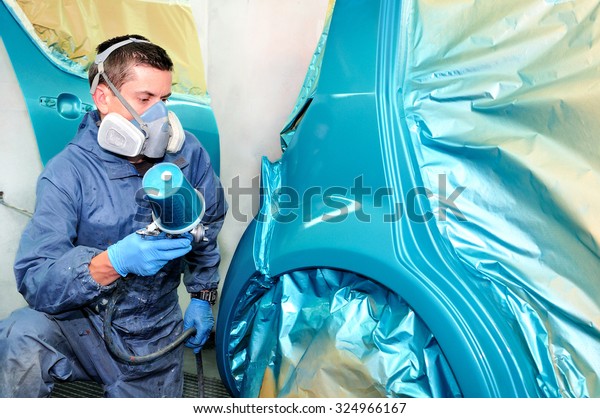 Car painter at work\
spraying blue.