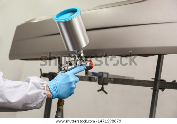 car\
painter\'s hand is painting a car detail with spray gun. painting a\
car part in a spray booth by pulverizer close\
up