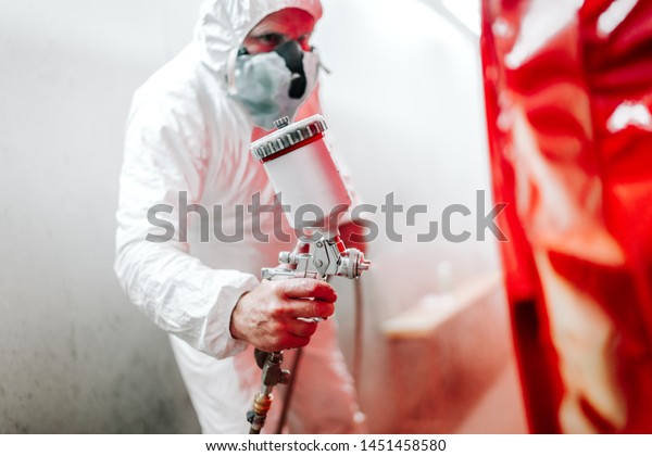 car painting details in\
automotive manufacturing industry. worker painting a car in special\
booth