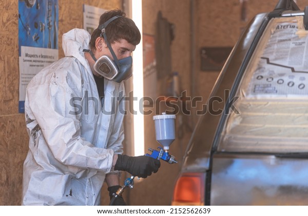Car painting and repair service. Paints\
the car with an airbrush in the spray booth. A car worker sprays\
paint on a car. DNIPRO, UKRAINE - April 29,\
2022