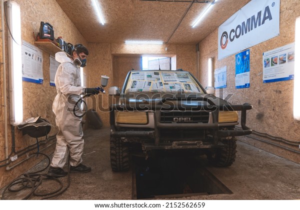Car painting and repair service. Paints\
the car with an airbrush in the spray booth. A car worker sprays\
paint on a car. DNIPRO, UKRAINE - April 29,\
2022